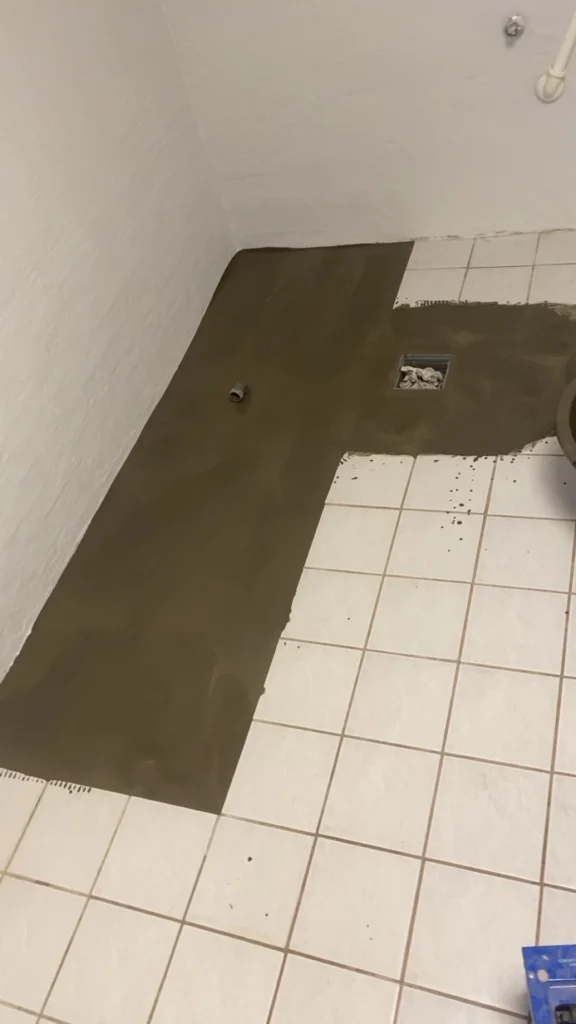 Flydespartel lagt i badeværelse for at rette voldsomt fald ved afløb, som klargøring til microcement